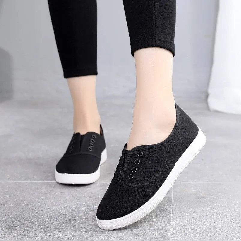Low-top casual canvas shoes on a flat heel, shown in various colours including black, white, grey, and pink.