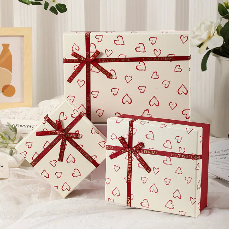 Cardboard gift box with bow in red, green, and pink, multiple sizes for gifts