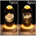 Clear crystal ball LED night light showing a 3D galaxy or planet design, lit from within on a table.