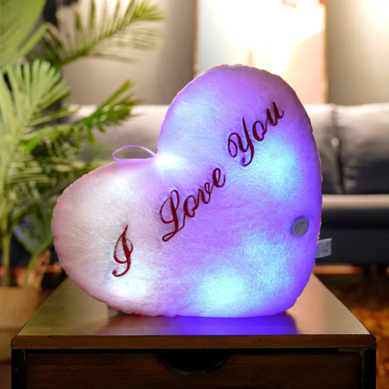 Colourful glowing five-pointed star plush pillow on a dark background, showing soft texture and LED illumination