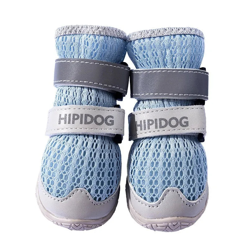 Pair of light blue breathable dog shoes with a cartoon style on a wooden floor.