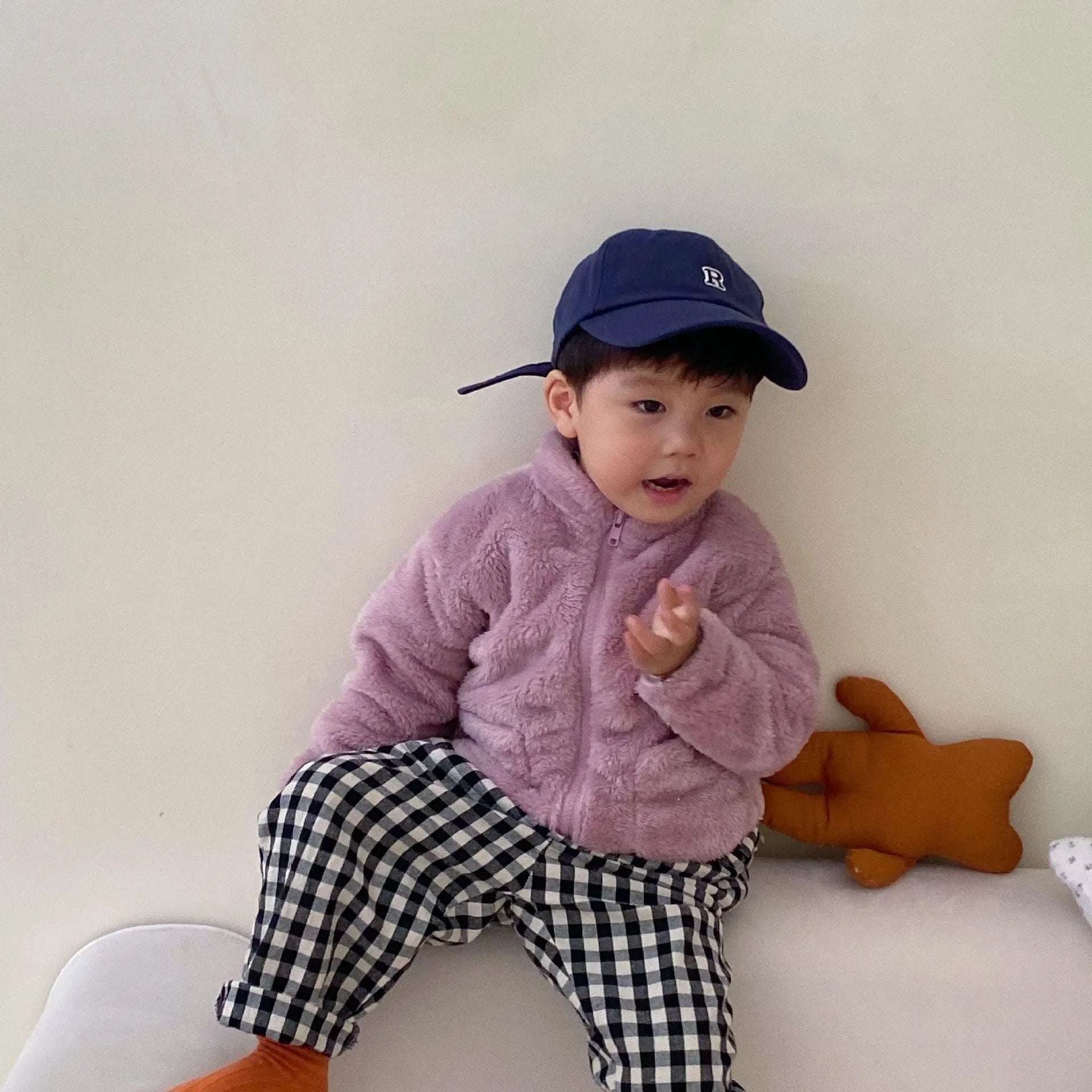 A child wearing a blue sherpa fleece winter coat with a full zip, high collar, and front pockets.