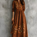 Brown suede-look midi dress with detailed floral embroidery on the bodice and hem, featuring three-quarter sleeves.