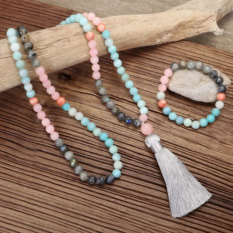 Bohemian style necklace and bracelet set with colourful drop-shaped stone pendants and tassel details on a white background