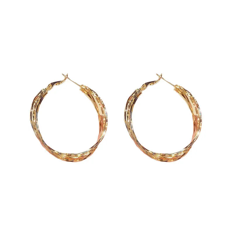 Gold and silver twisted metal earrings with copper body, round geometric shape, and silver needle for women.