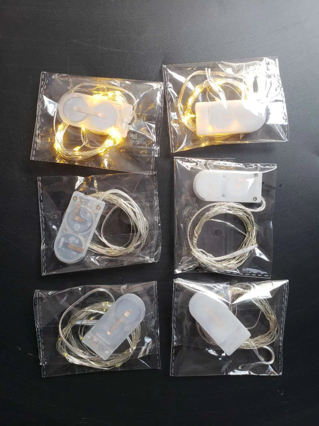 Copper wire LED button light string shaped into a spiral, powered by a small white battery box.