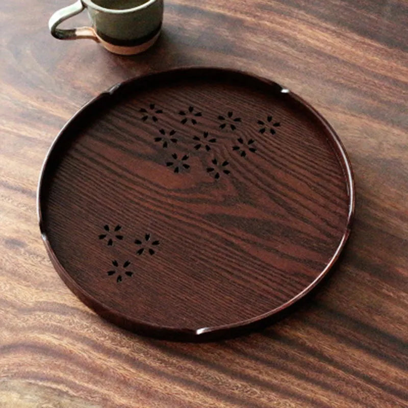 Wooden shallow plate with carved hollow cherry blossom pattern, shown from above.