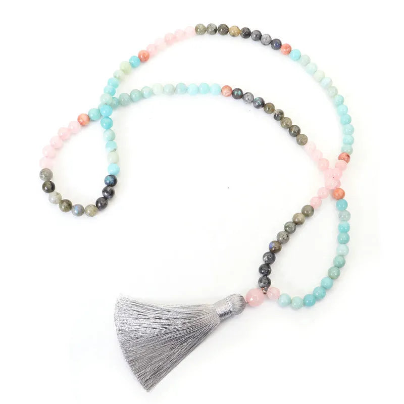Bohemian style necklace and bracelet set with colourful drop-shaped stone pendants and tassel details on a white background