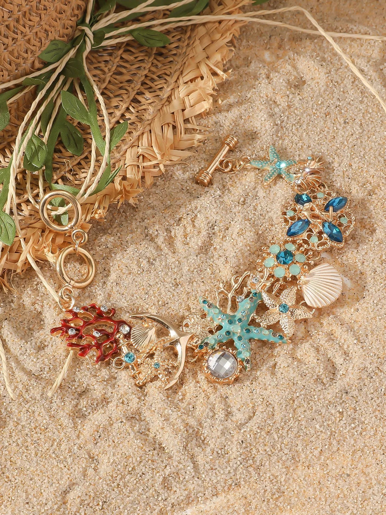 Alloy rhinestone bracelet with boat anchor, shell, and starfish charms in turquoise, red, or blue.