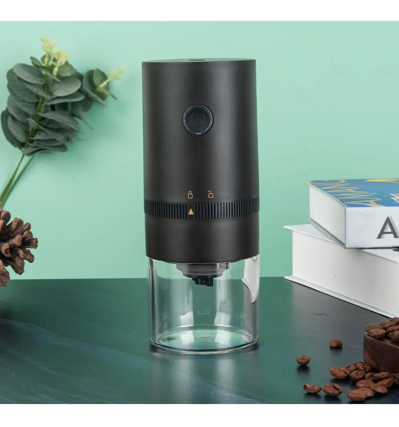Black and white portable USB-C electric coffee grinder with transparent chamber on a kitchen counter