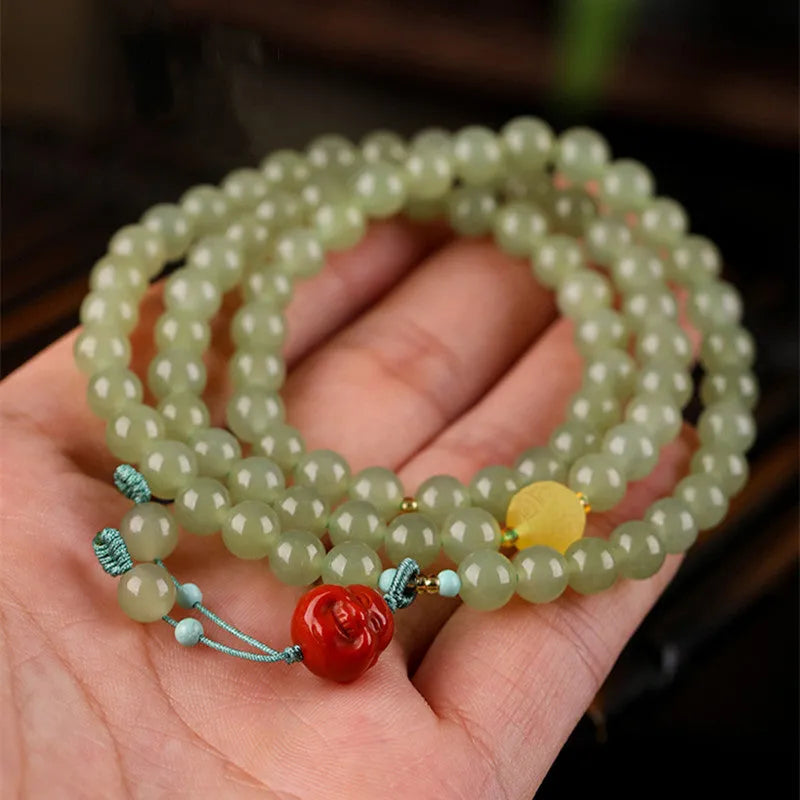 Pale blue Hetian jade bracelet with three circle design and 6mm beads on a wrist.