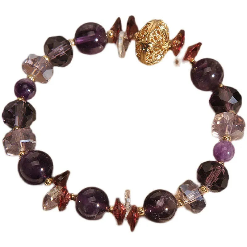Purple crystal bracelet with pumpkin beads, wind chime charms, and rhinestone details on a wrist.