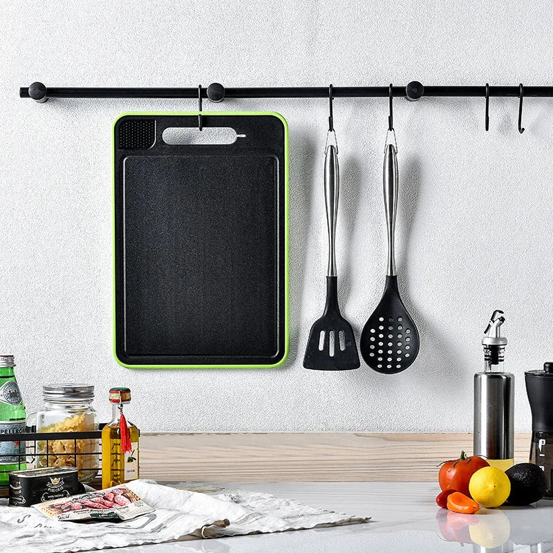 Grey square aluminium cutting board with defrosting side, grinder teeth, and integrated knife sharpener.
