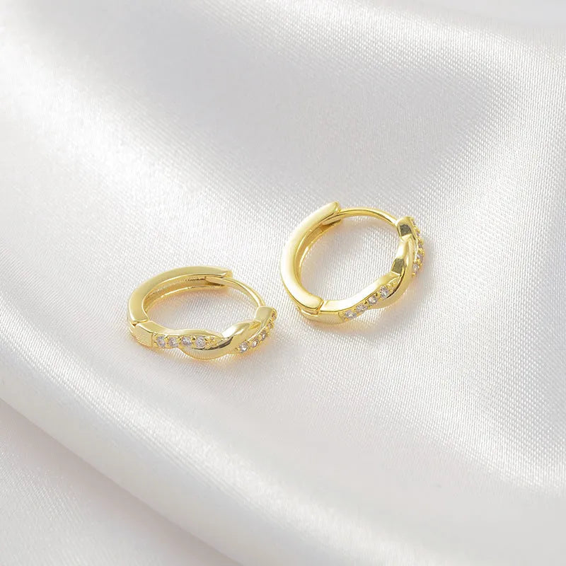 Close-up of women's geometric ear clips with interwoven hemp rope centre in gold tone.