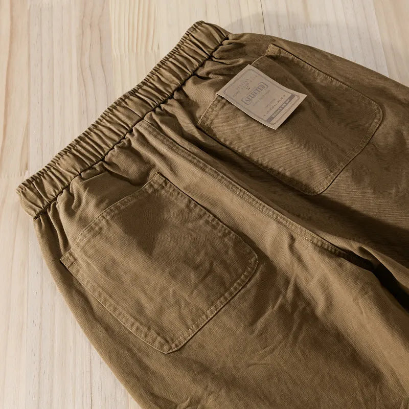Men's army green cotton drawstring overalls with ankle bands laid flat.