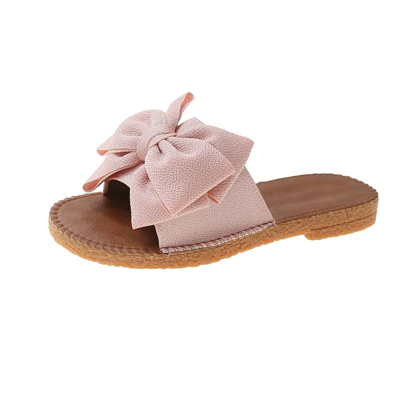 Women's beige slip-on sandals with bow detail and flat rubber sole