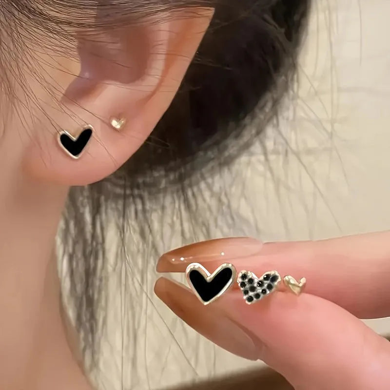 Three pairs of girly heart-shaped alloy earrings in gold, black, pink, and black and white colours.