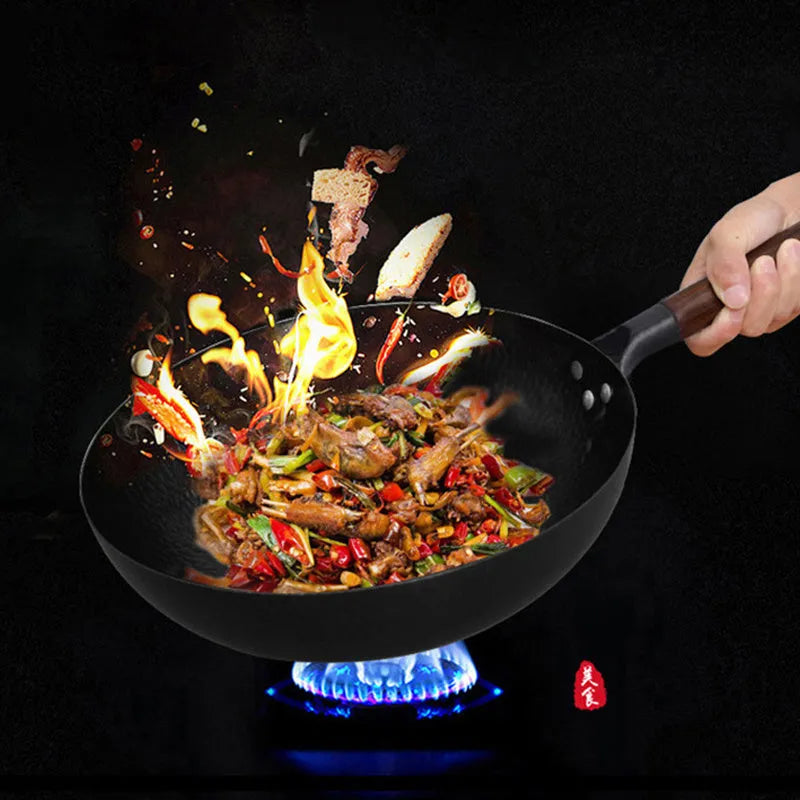 Handmade black iron wok pan with a long wooden handle on a kitchen counter.
