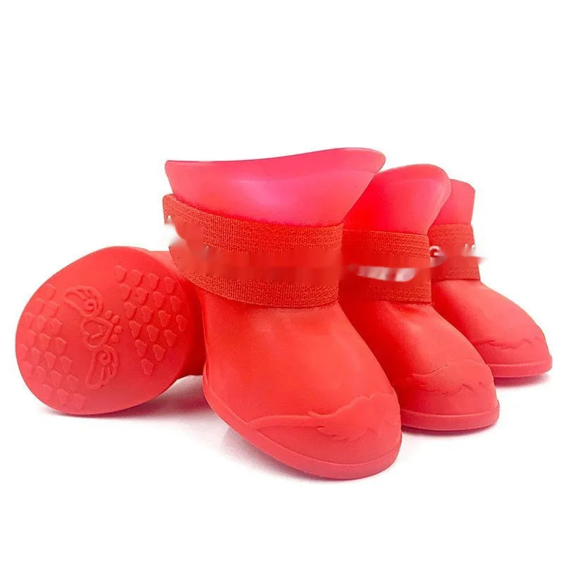 Set of four colourful rubber dog rain shoes with anti-slip soles on a wet surface.
