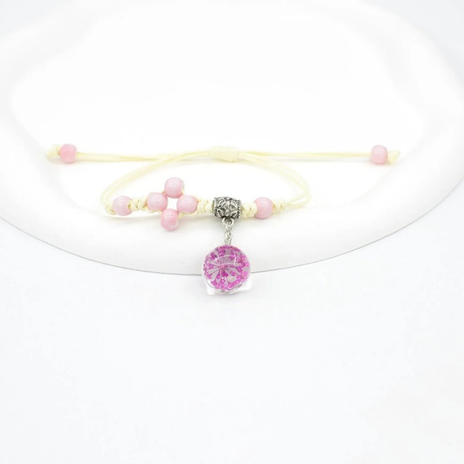 Close-up of a hand-woven glass bracelet with large 1.4cm beads containing real dried flowers and lace floral detailing.