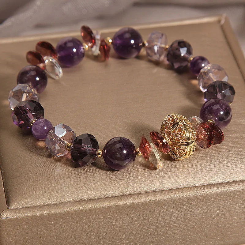 Purple crystal bracelet with pumpkin beads, wind chime charms, and rhinestone details on a wrist.