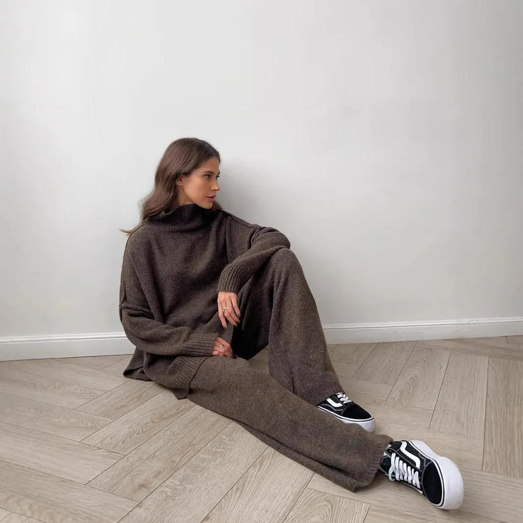 Women's dark grey acrylic sweater with side slits and matching full-length trousers laid flat.