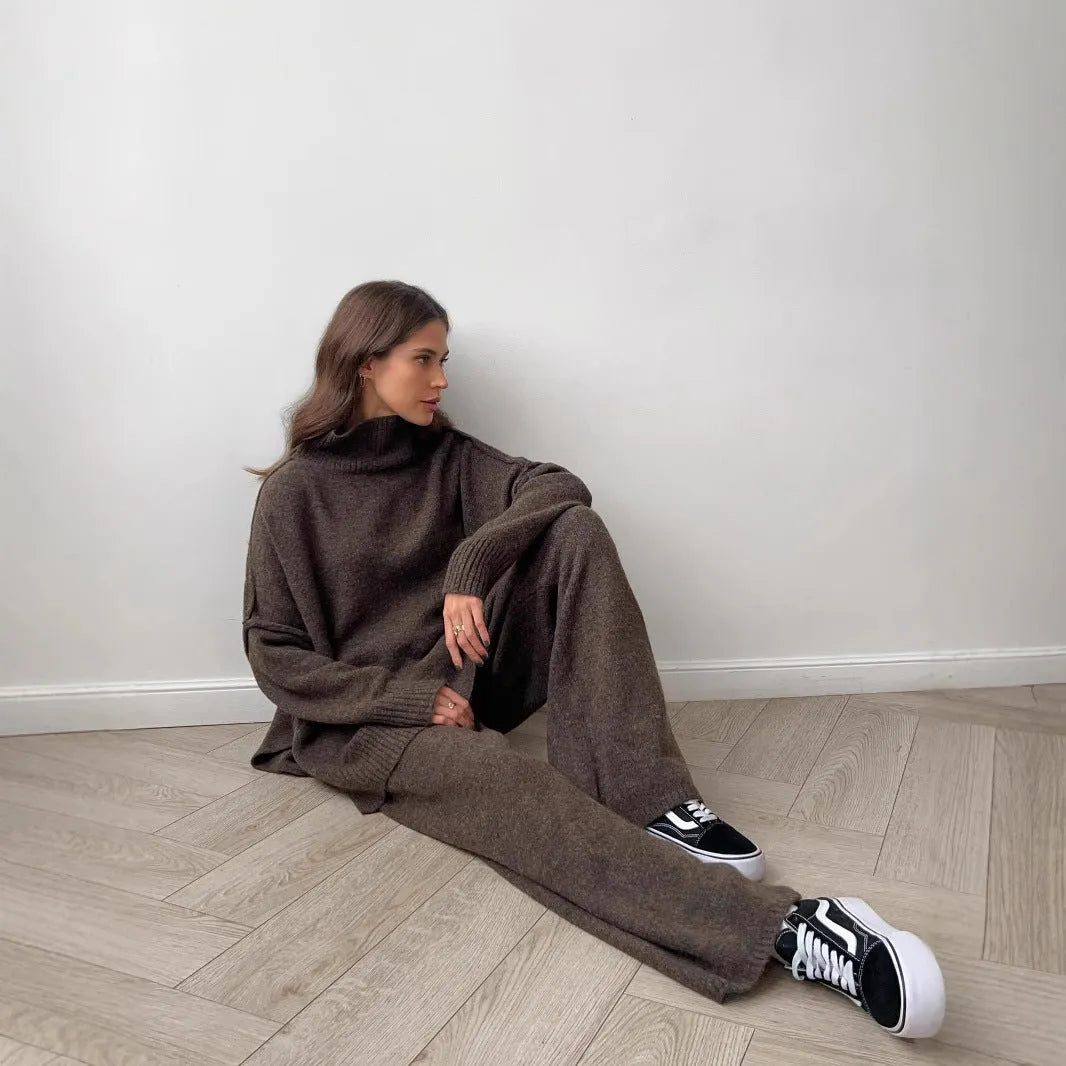 Women's dark grey acrylic sweater with side slits and matching full-length trousers laid flat.