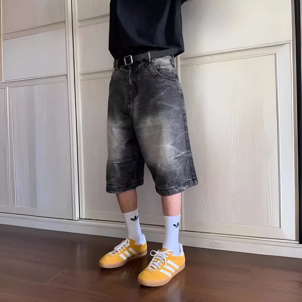 Man wearing loose-fit light blue washed denim shorts with a straight leg and cropped length.