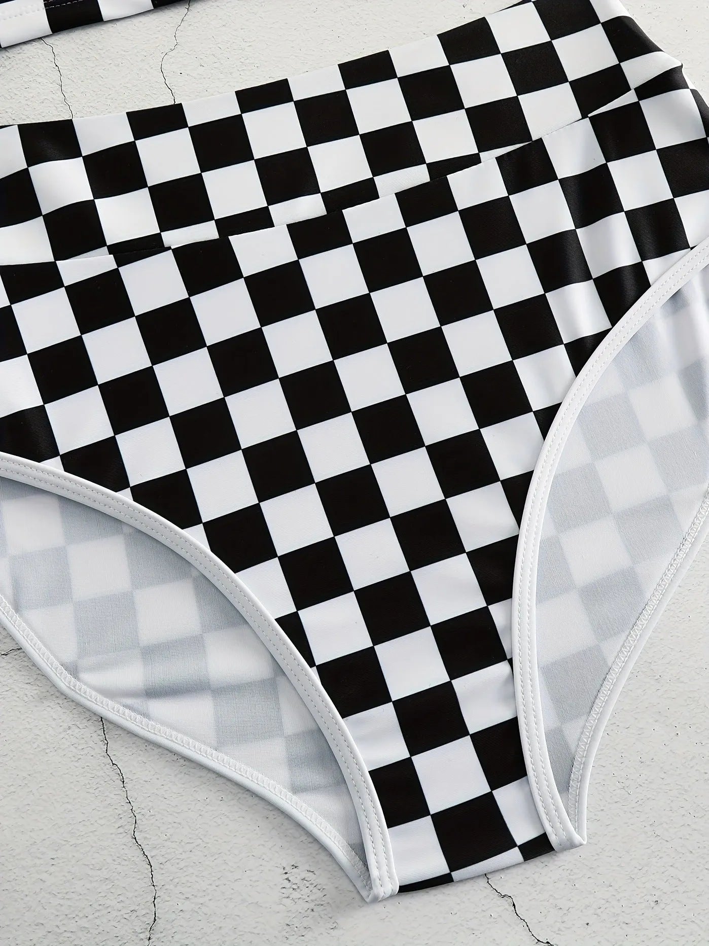 Women's black and white checkerboard plaid backless racing swimsuit with suspender straps.
