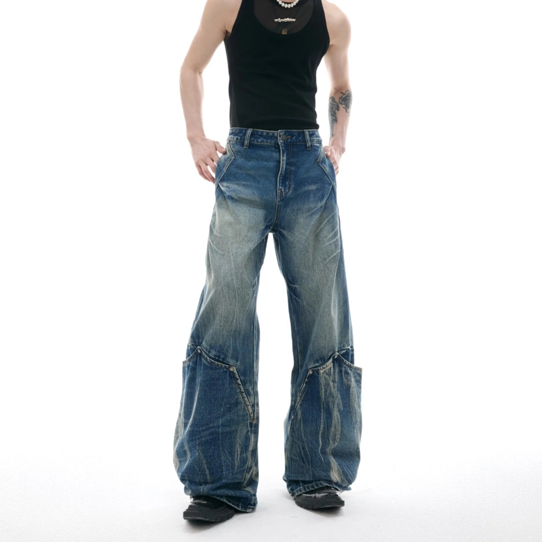 Man wearing verdant blue loose-fit retro jeans with a curved knife washed pattern on the legs.