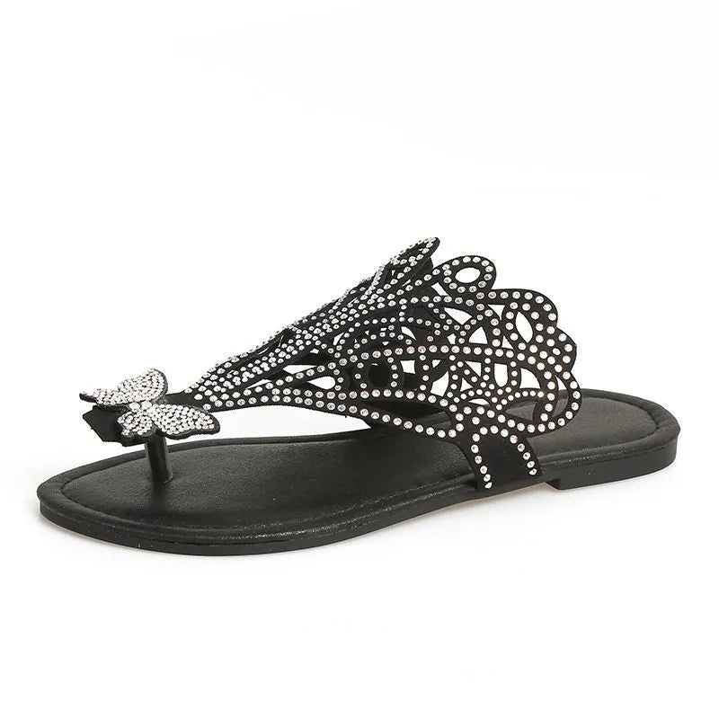 Women's black slip-on sandals with rhinestone decoration on the toe, showing flip-toe and flat rubber sole design.