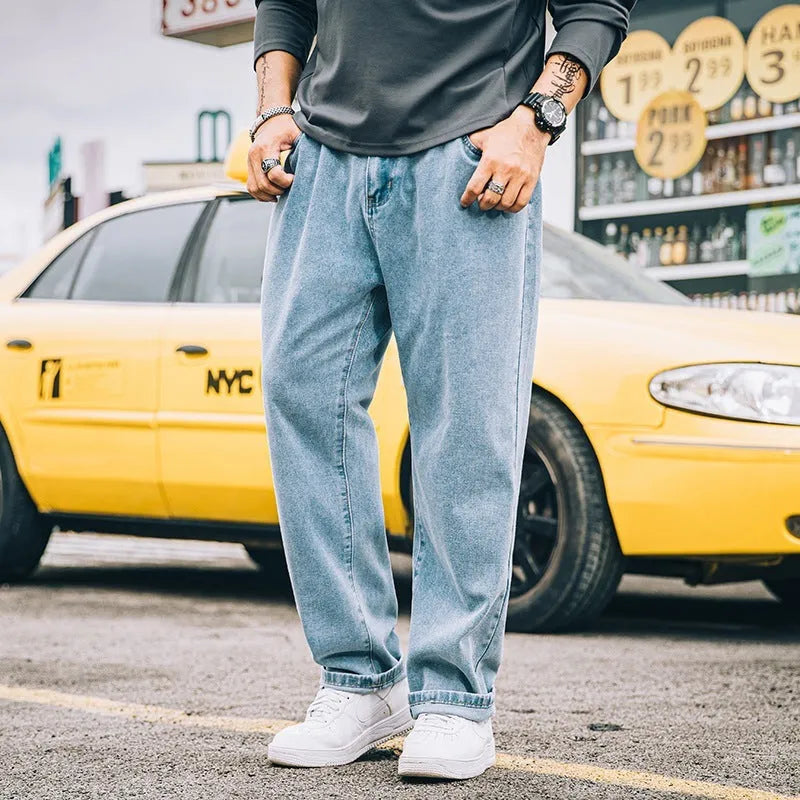 Man wearing dark blue loose straight-leg cotton jeans with a simple design and zipper fly.