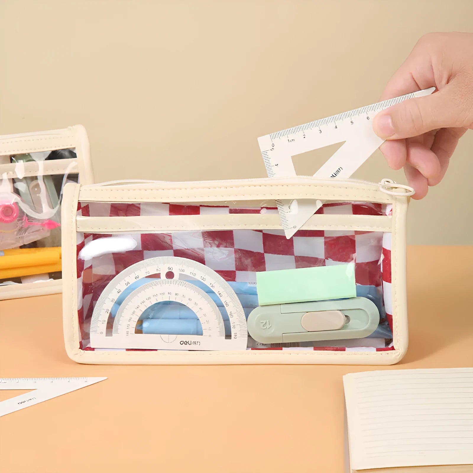 Transparent PVC pencil case with chessboard grid pattern, showing pens inside.