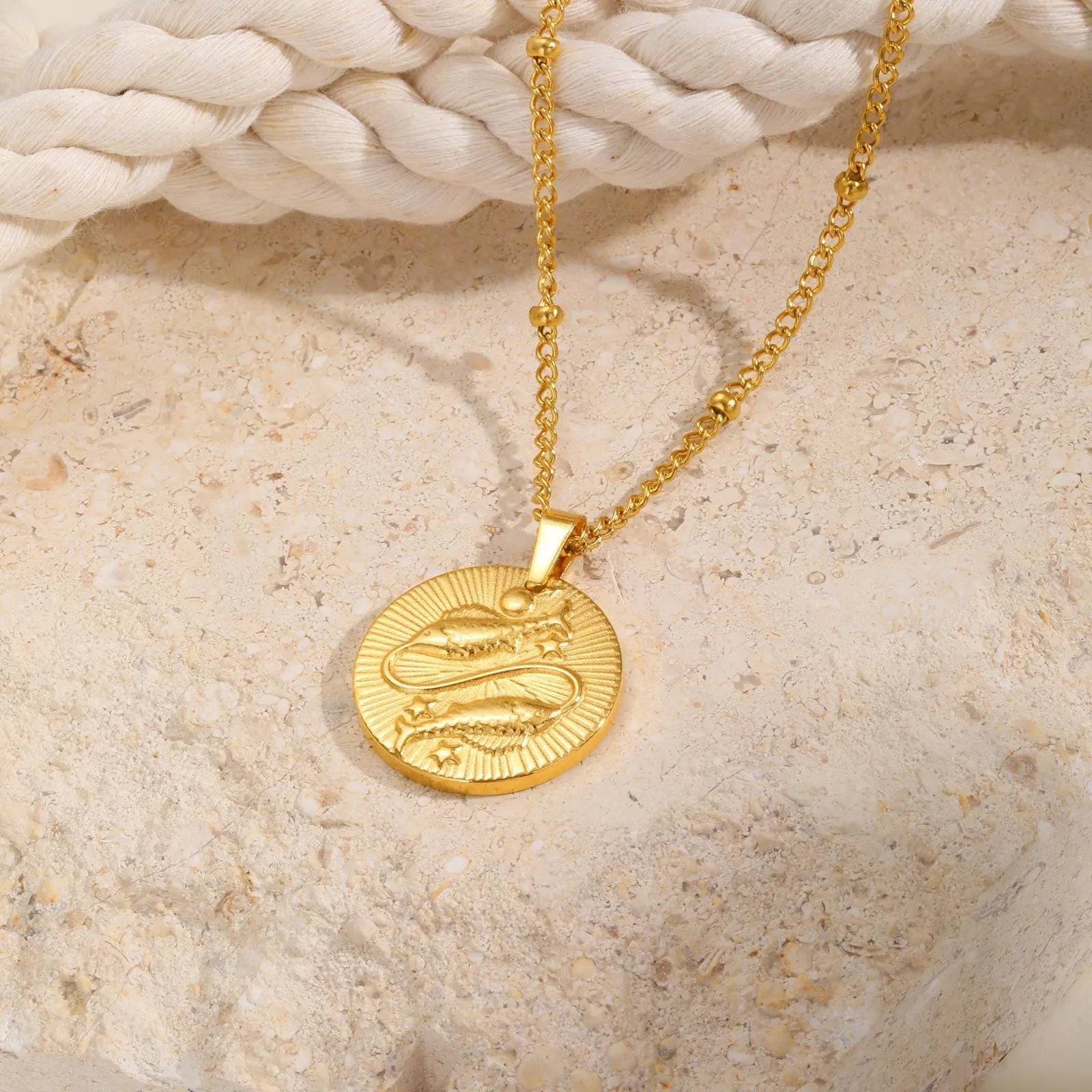 Stainless steel cross chain necklace with a geometric round bead pendant embossed with a zodiac constellation design.