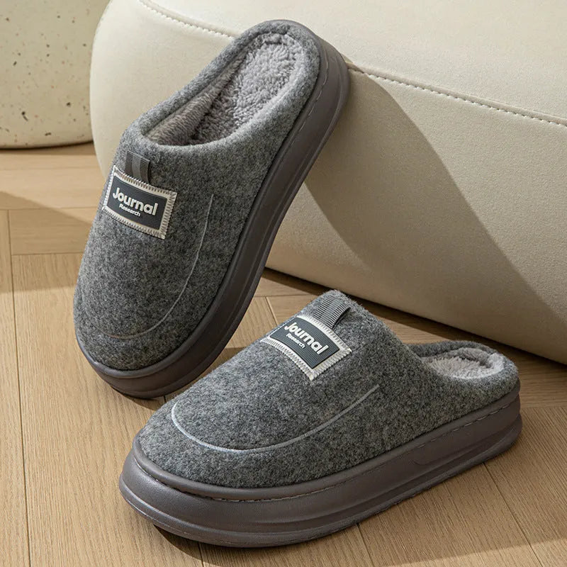Men's brown suede slippers with a thick, textured sole on a wooden floor