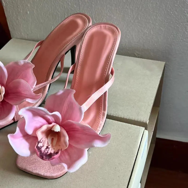Pink satin women's high heel sandals with a square toe and a white artificial flower decoration.