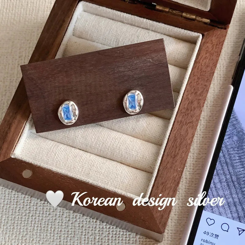 Silver geometric earrings with oval blue diamond wrapped in heart motif