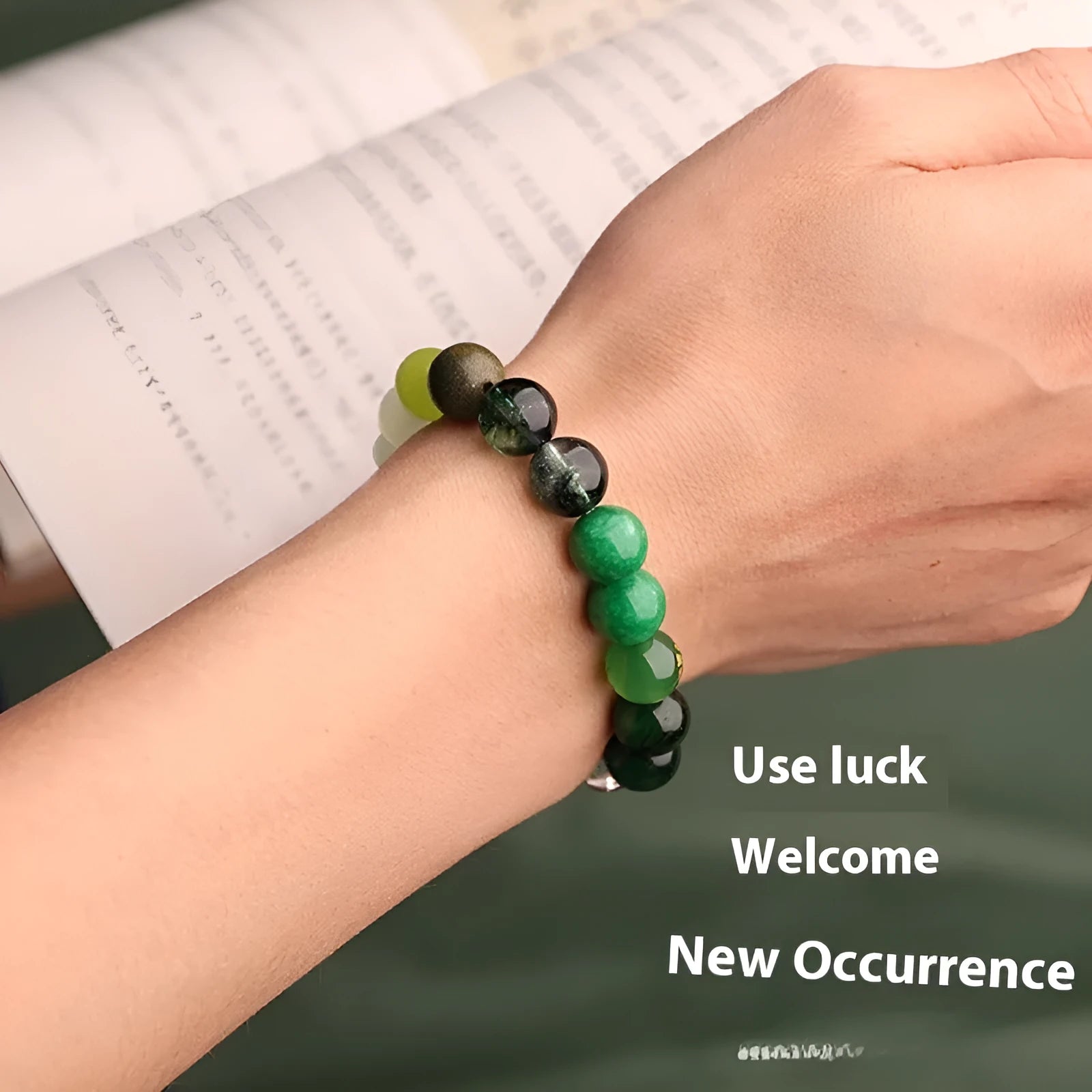 Green agate energy balance bracelet with metal lucky cat and auspicious charm on a wooden surface.