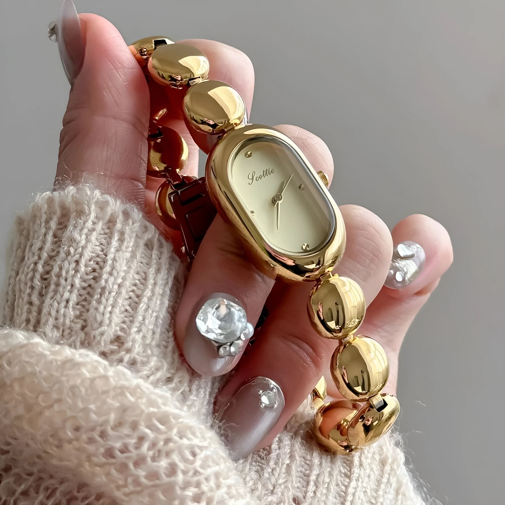 Oval women's fashion watch on wrist showing 9mm thick case, available in black gold, platinum and other colours.
