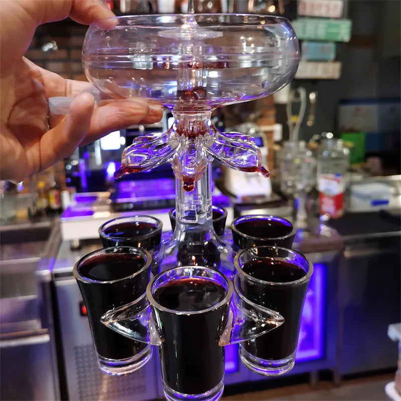 Clear six-shot glass dispenser holder with rack and six cups on a bar table.