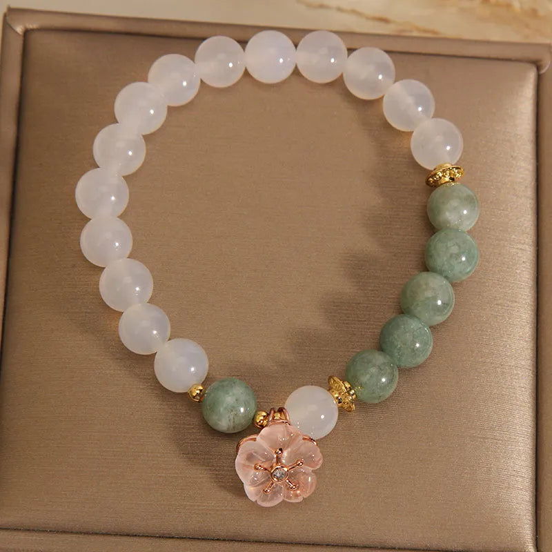 White agate jade bracelet with floral shape on a casual model wrist.