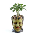 Green Man resin flower pot with sculptural relief detail on white desktop