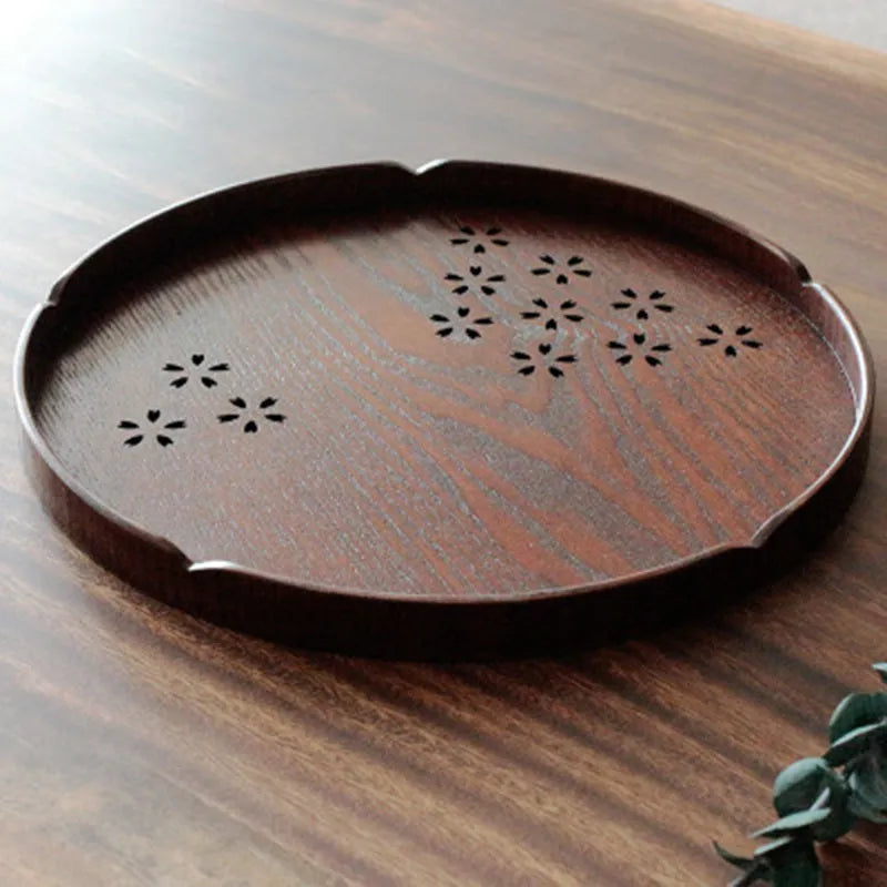Wooden shallow plate with carved hollow cherry blossom pattern, shown from above.