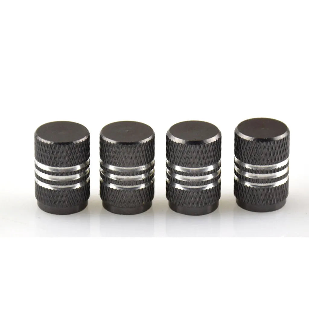 Set of coloured aluminium alloy tyre valve caps for car wheels on a grey background.