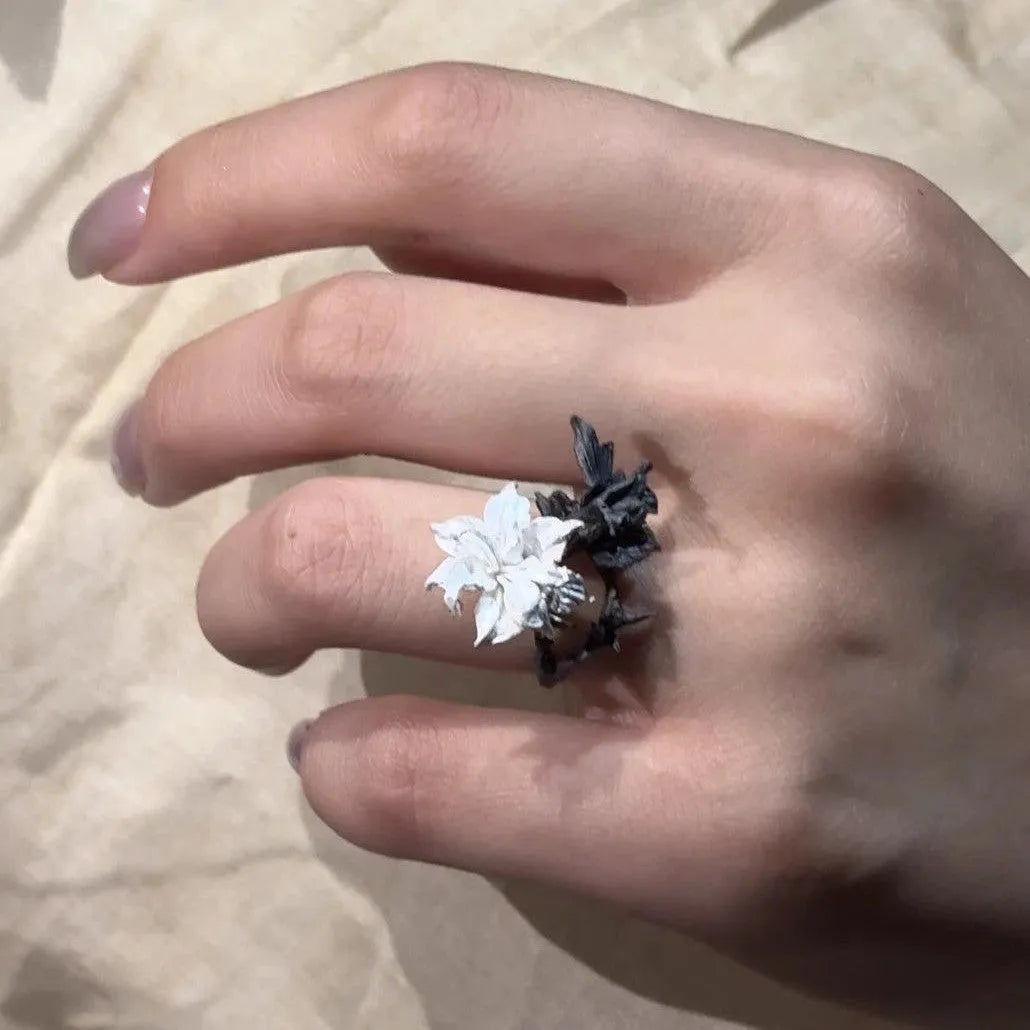 Open mouth copper ring with white and black colour separation and lily motif on a plain background