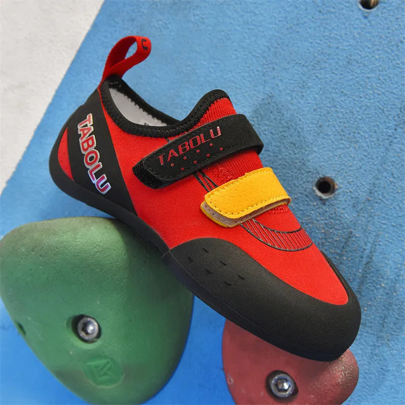 A pair of beginner rock climbing shoes with velcro straps in a black and red colour combination.