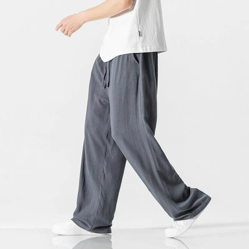 Man wearing beige straight-leg cropped bamboo fibre trousers with a drawstring waist on a summer day.