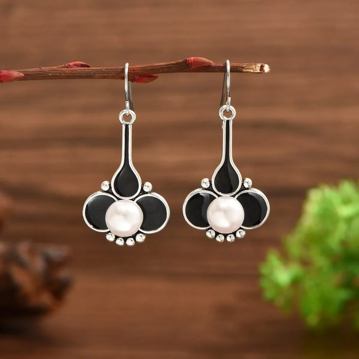 Pair of silver colour retro creative drop dangle earrings for women on a white background.