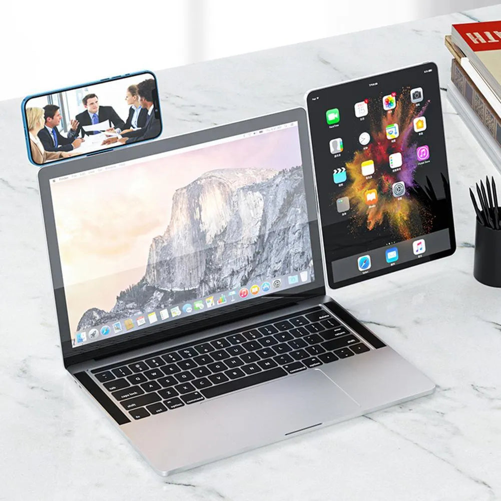 Black magnetic phone holder attached to side of silver laptop, showing phone mounted.
