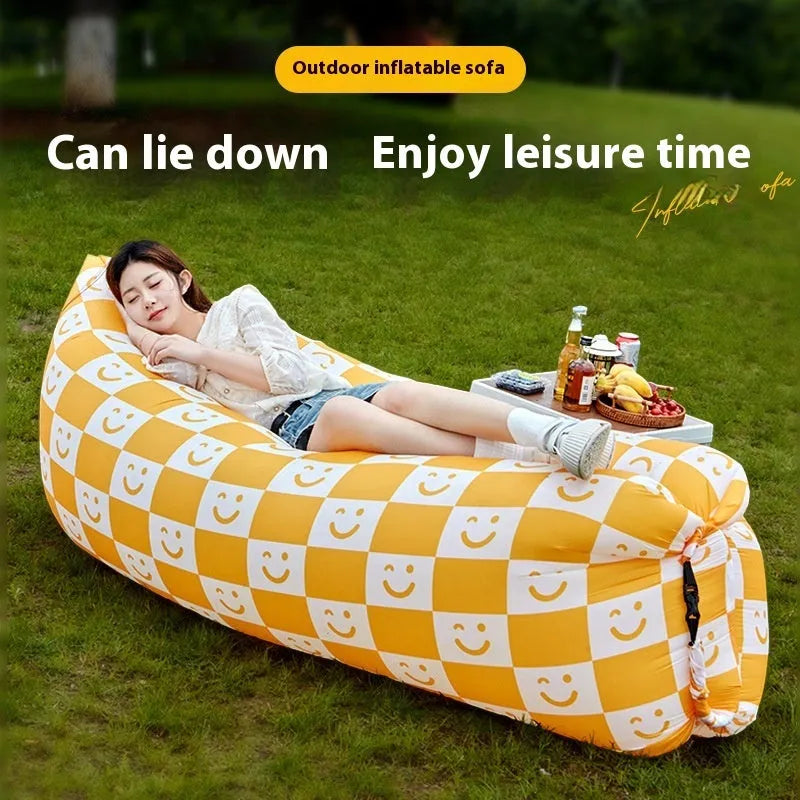 Inflatable lazy sofa in yellow smiling face tip colour, folded for transport with one-minute inflation valve visible